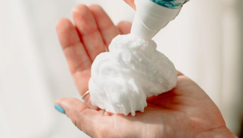 Woman spraying dry shampoo bottle.