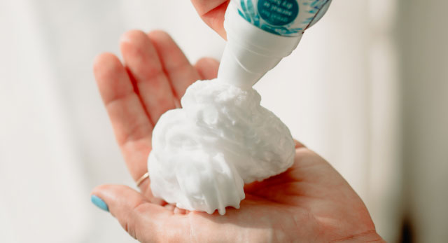 spraying Waterless Cleansing Foam Dry Shampoo With Coconut Milk onto hand